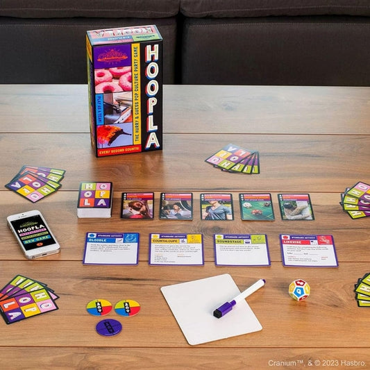 Hoopla board game components on a wooden table with Hasbro logo.