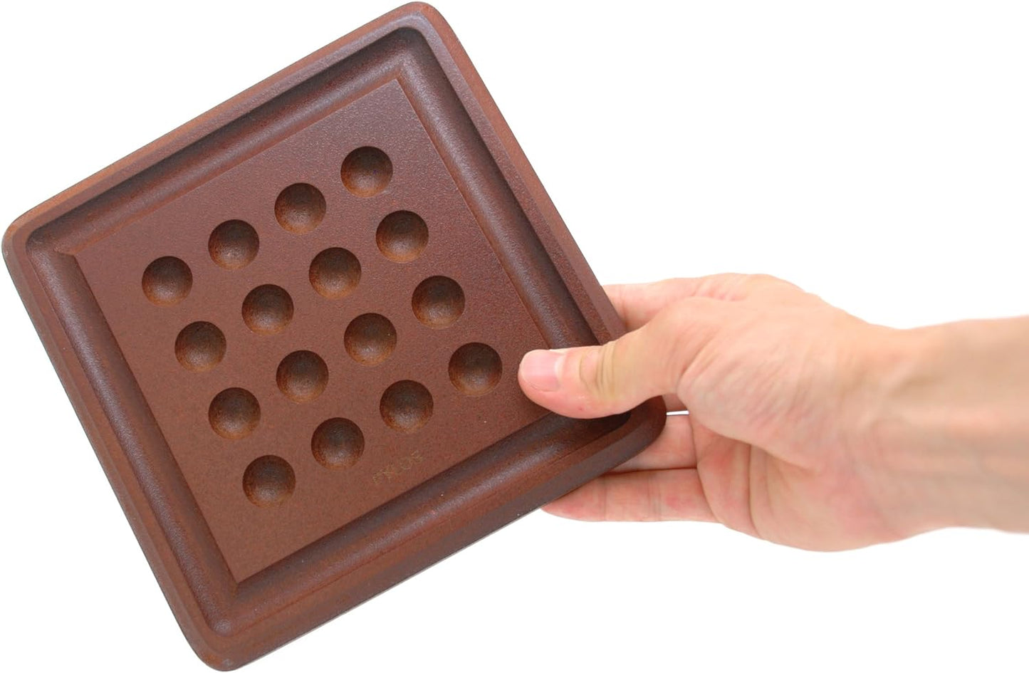 Hand holding a wooden game board for Pylos mini by Gigamic on a white background