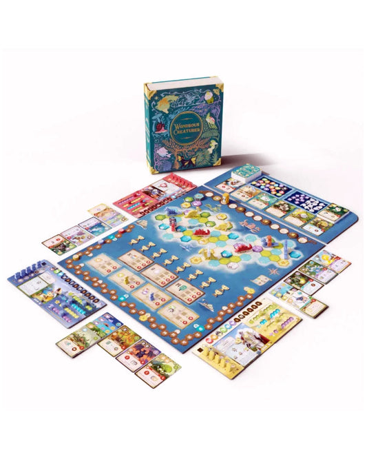Wondrous Creatures board game set arranged on a white background, including a large blue game board, a matching game box, cards, tokens, and small accessory pieces.