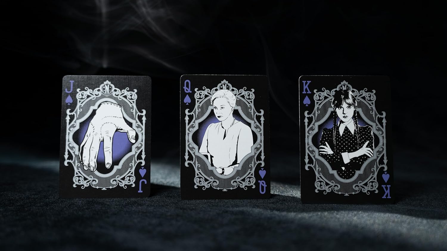 Three playing cards with decorative frames and portraits on a dark background