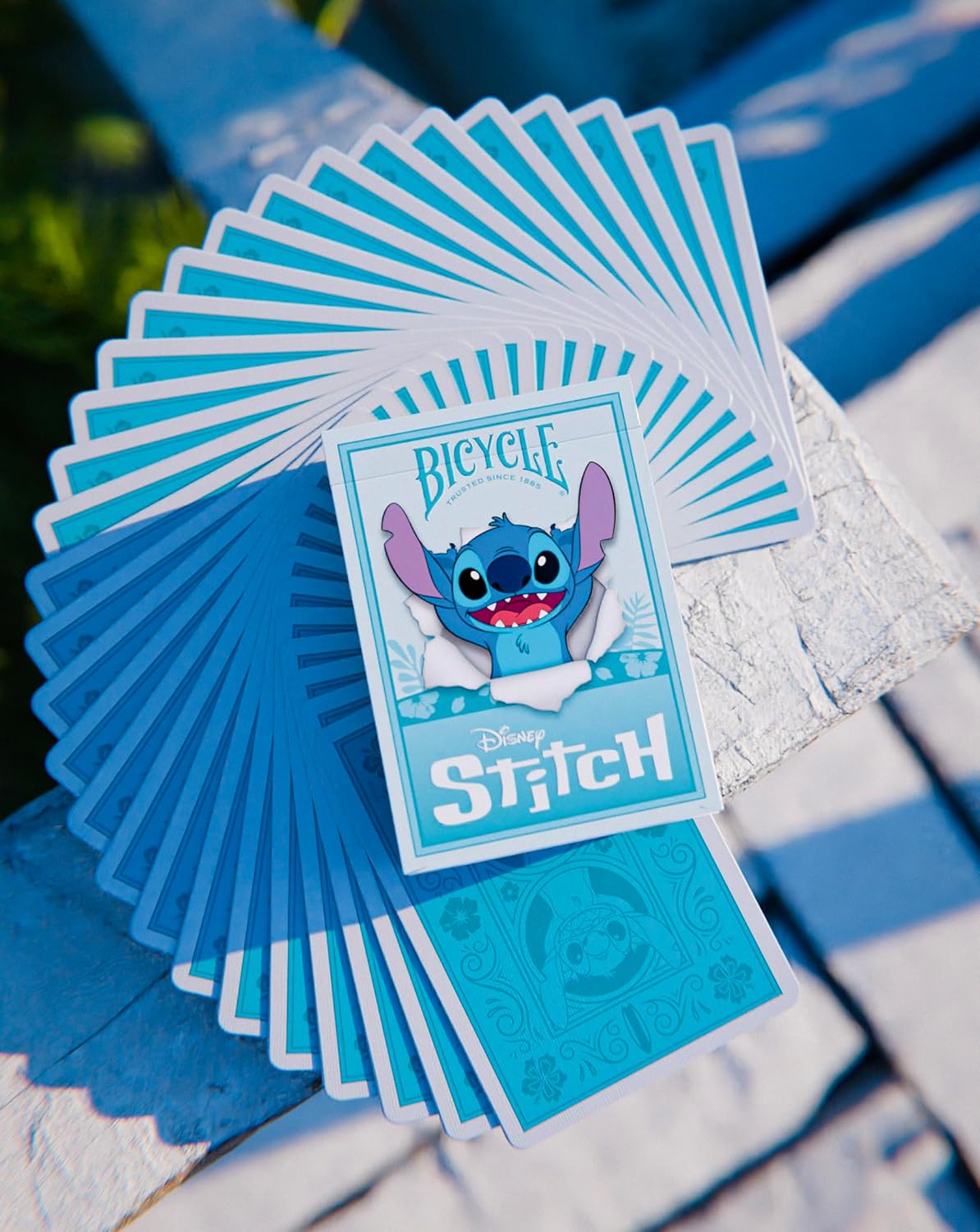 Deck of Bicycle Disney Stitch playing cards fanned out on a textured surface with a blue background.