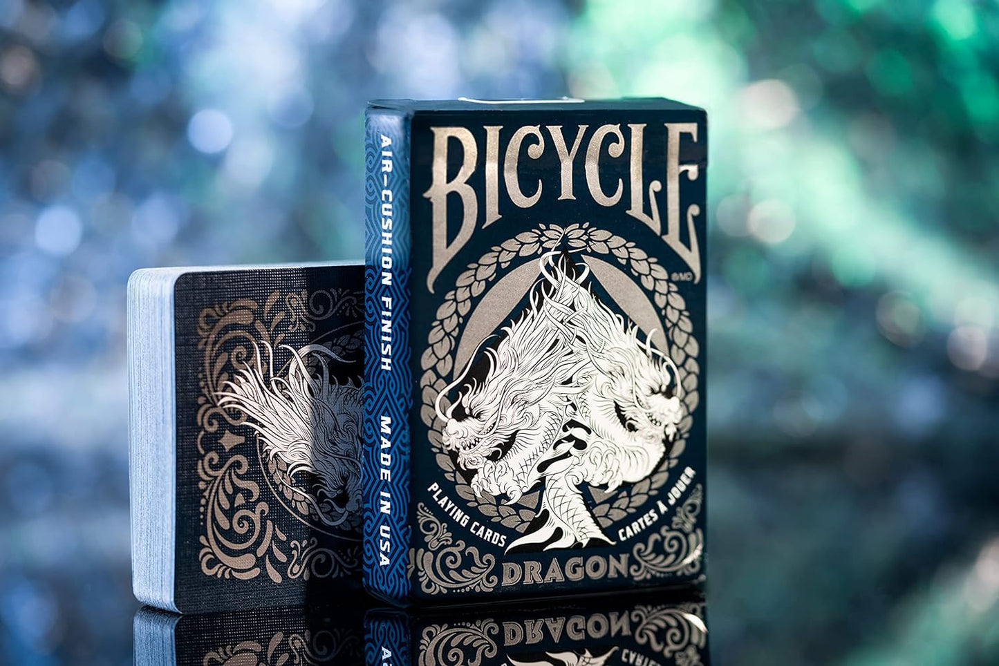 Bicycle Dragon playing cards with intricate design on a reflective surface.