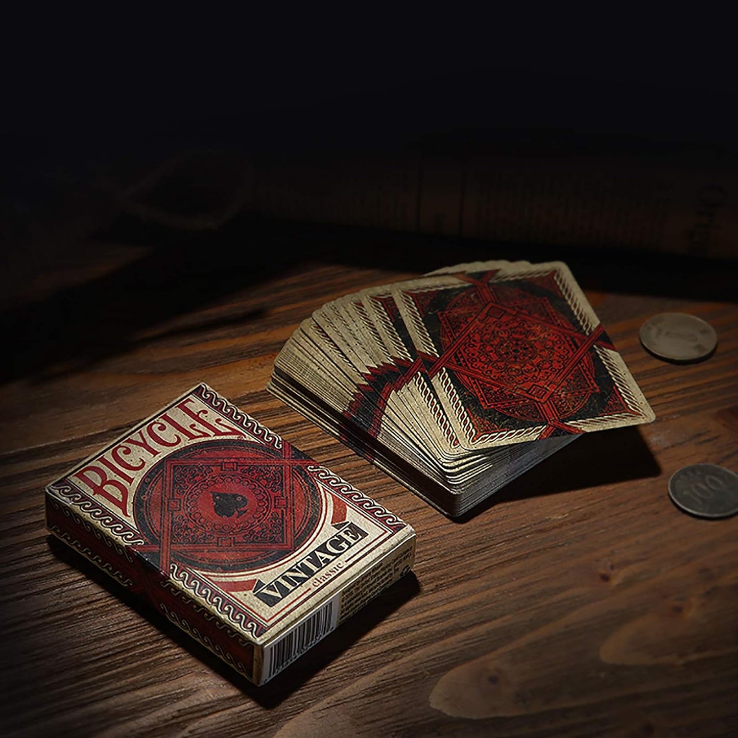 Bicycle Vintage Playing Cards in red and gold stacked on wooden table