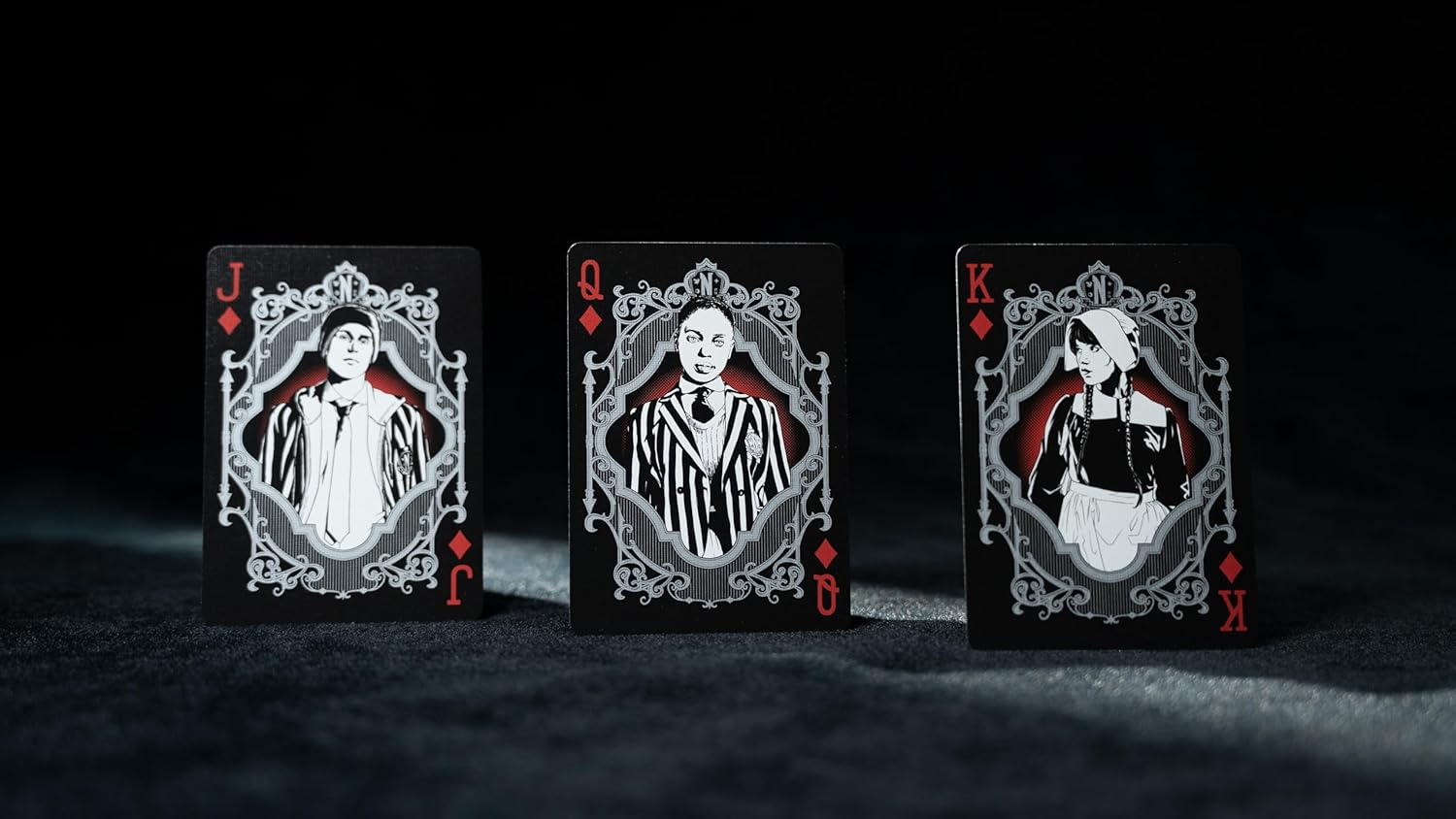 Three playing cards with decorative designs on a dark background