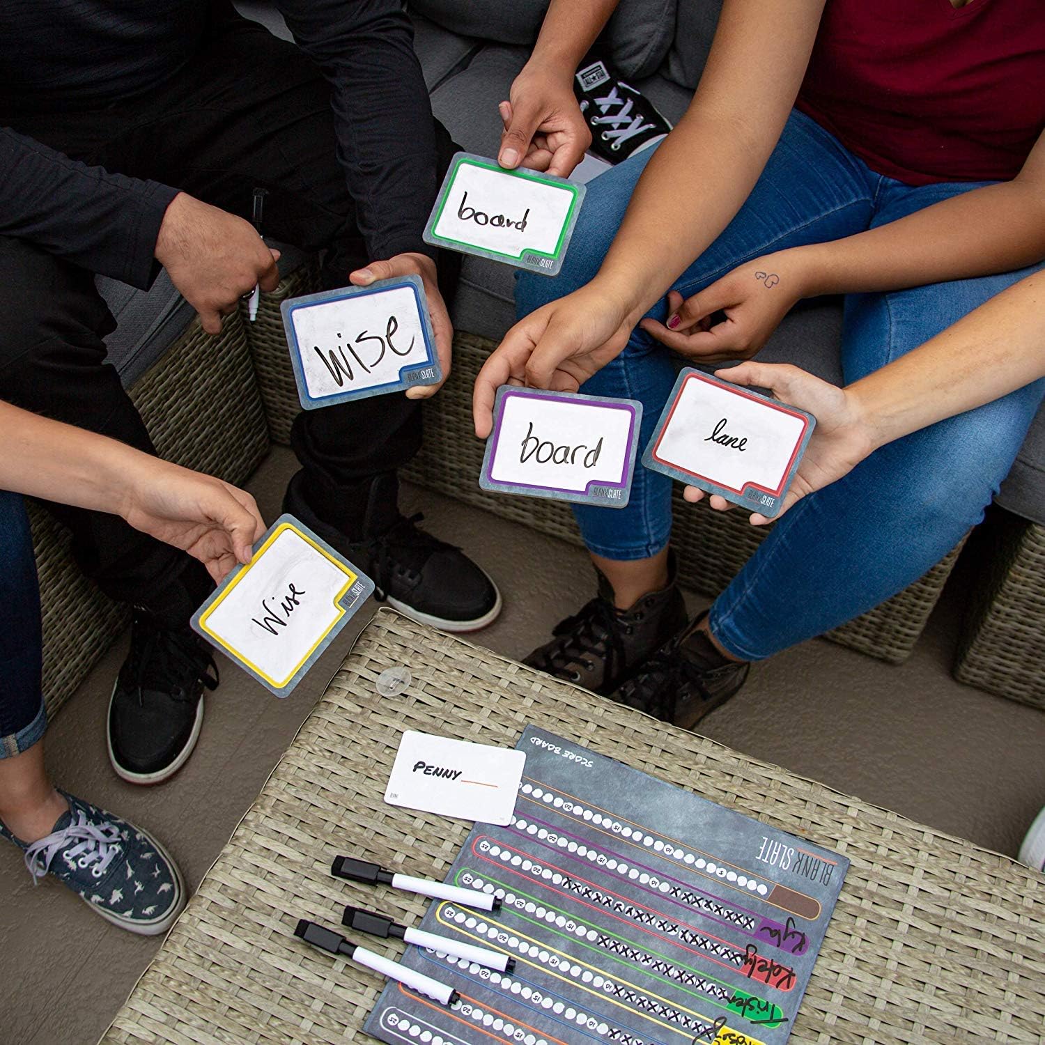Group of people holding Blank Slate cards with words on them, sitting around a table.