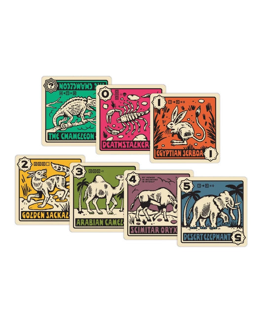 Desperate Oasis Tactical Card Game showing seven illustrated animal-themed cards arranged in two rows on a plain white background. The cards feature vintage-style artwork with cream borders and different colored panels: green, pink, orange, yellow, olive green, and blue-grey, with text including 'The Chameleon,' 'Death Instalker,' 'Egyptian Scorpion,' 'Golden Jackalope,' 'Arabian Camel,' 'Scimitar Ox,' and 'Desert Elephant.