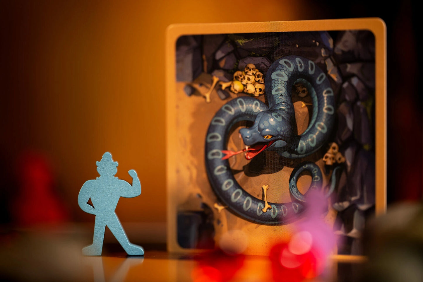 Diamant board game with figure of a warrior facing a dragon in a shadow box setting with warm lighting.
