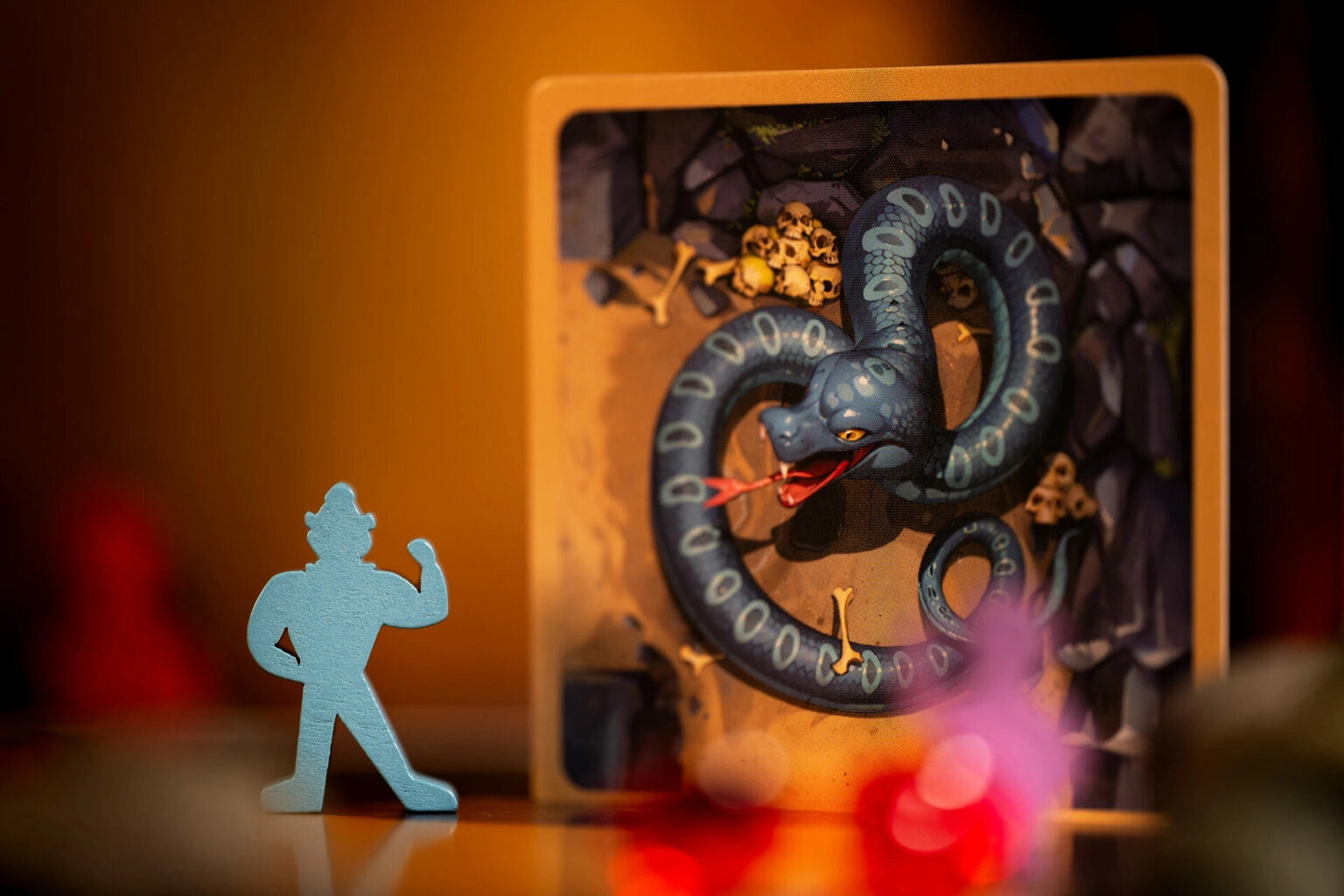 Diamant board game with figure of a warrior facing a dragon in a shadow box setting with warm lighting.