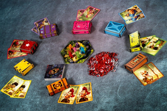Collection of colourful game cards and containers on a textured surface with red gemstones for Diamant board game.