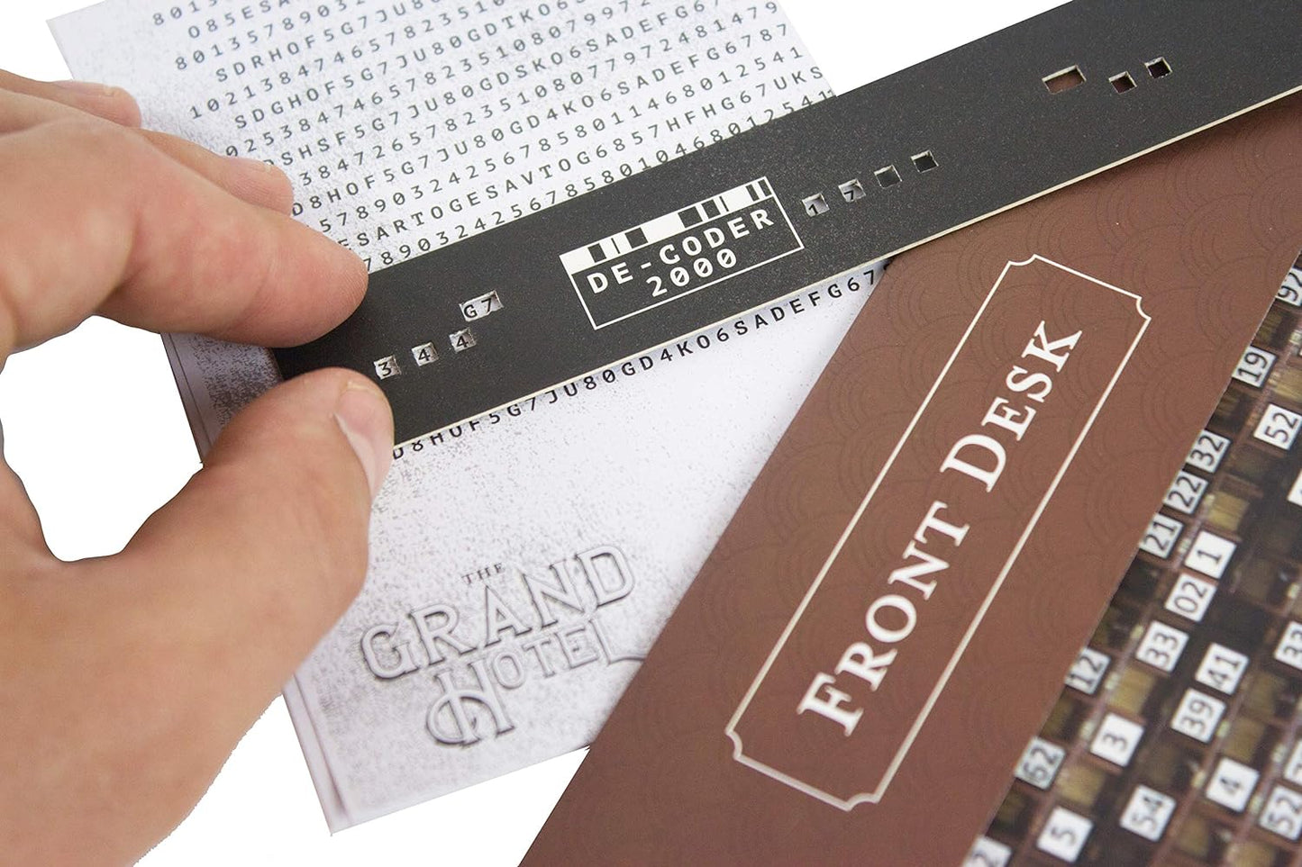 Hand holding a decoder over a document with text, next to a 'Front Desk' sign.