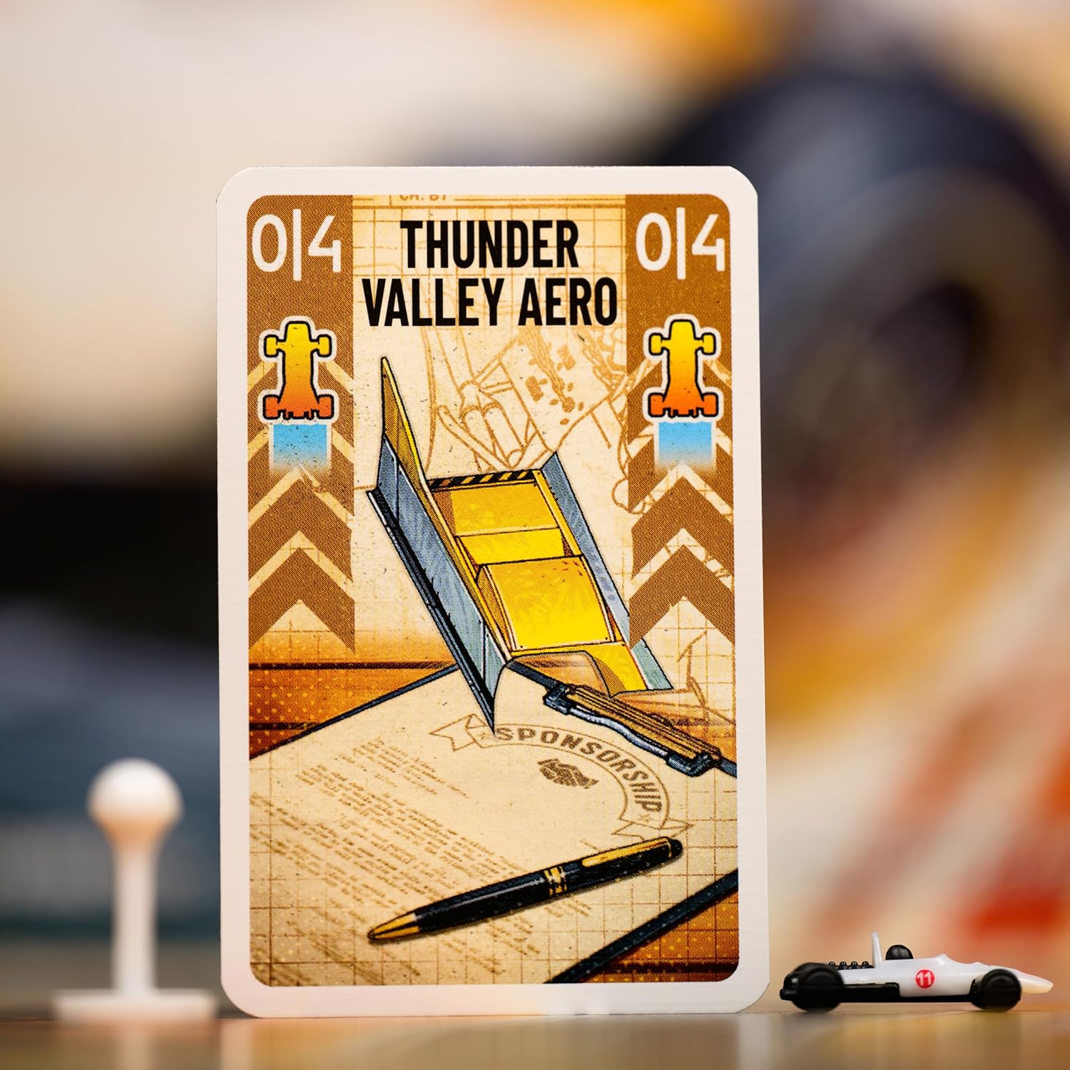 Card with 'Thunder Valley Aero' design featuring a blueprint and pen for Heat Rocky Roads board game on a blurred background
