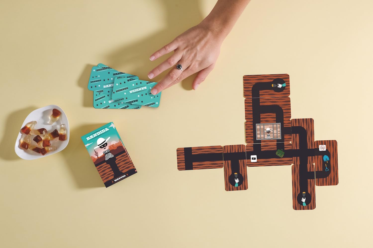 Hand playing a board game with colorful tiles on a beige surface