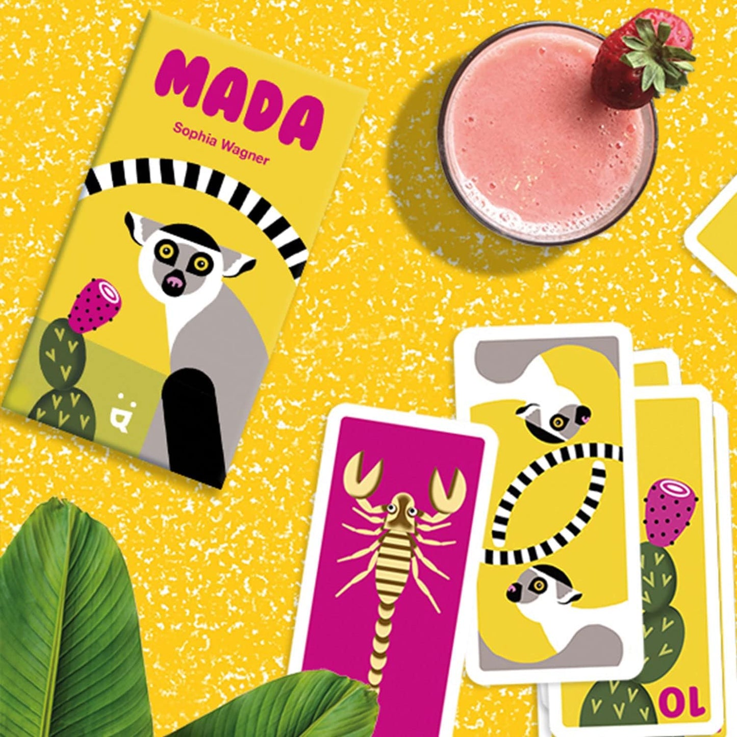 Card game titled 'Mada' with illustrations of a lemur and a scorpion on a yellow background with a pink smoothie.