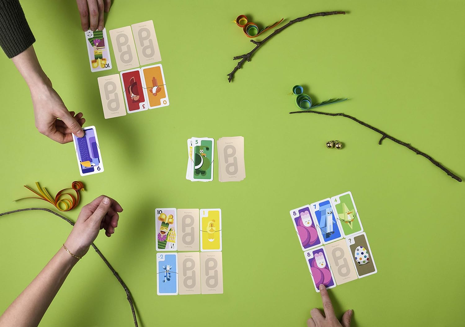 Card game being played on a green surface with cards and small figurines.