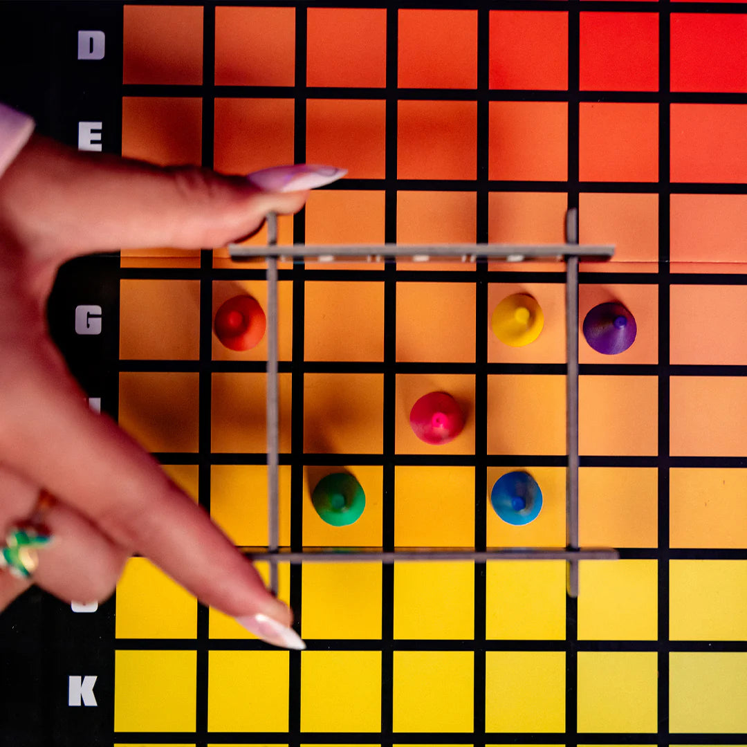Hues and Cues Colour swatch chart with a hand holding a metal grid over colored beads.