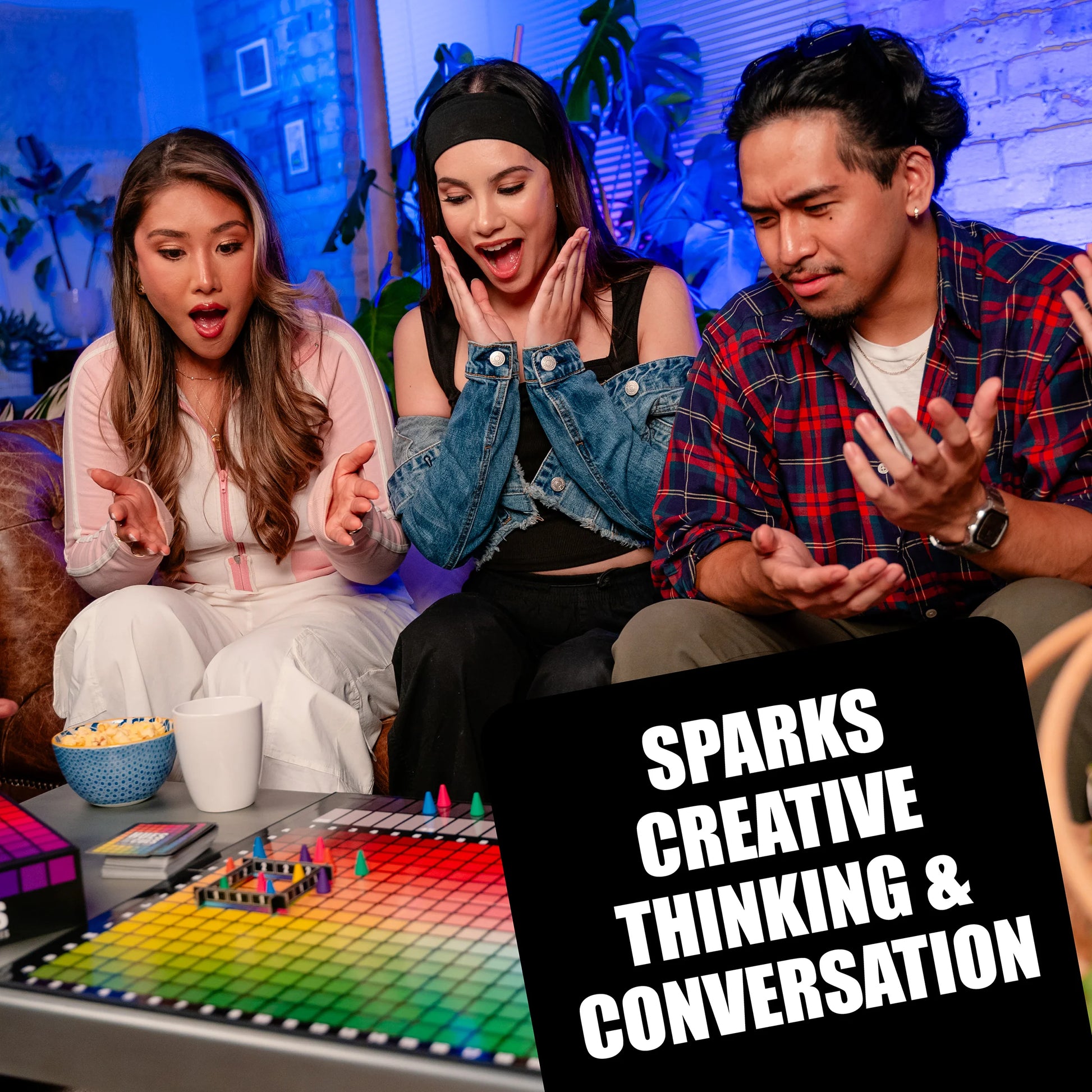 Three people sitting around a table playing Hues and Cues board game