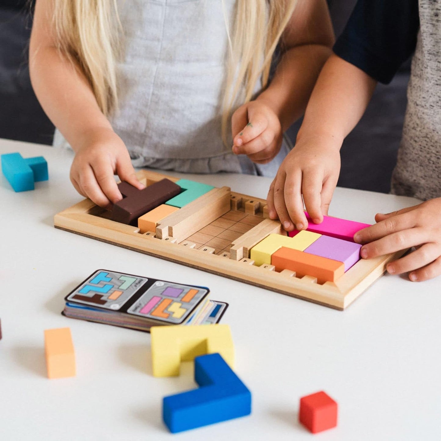 Children playing with colourful wooden blocks on a white surface