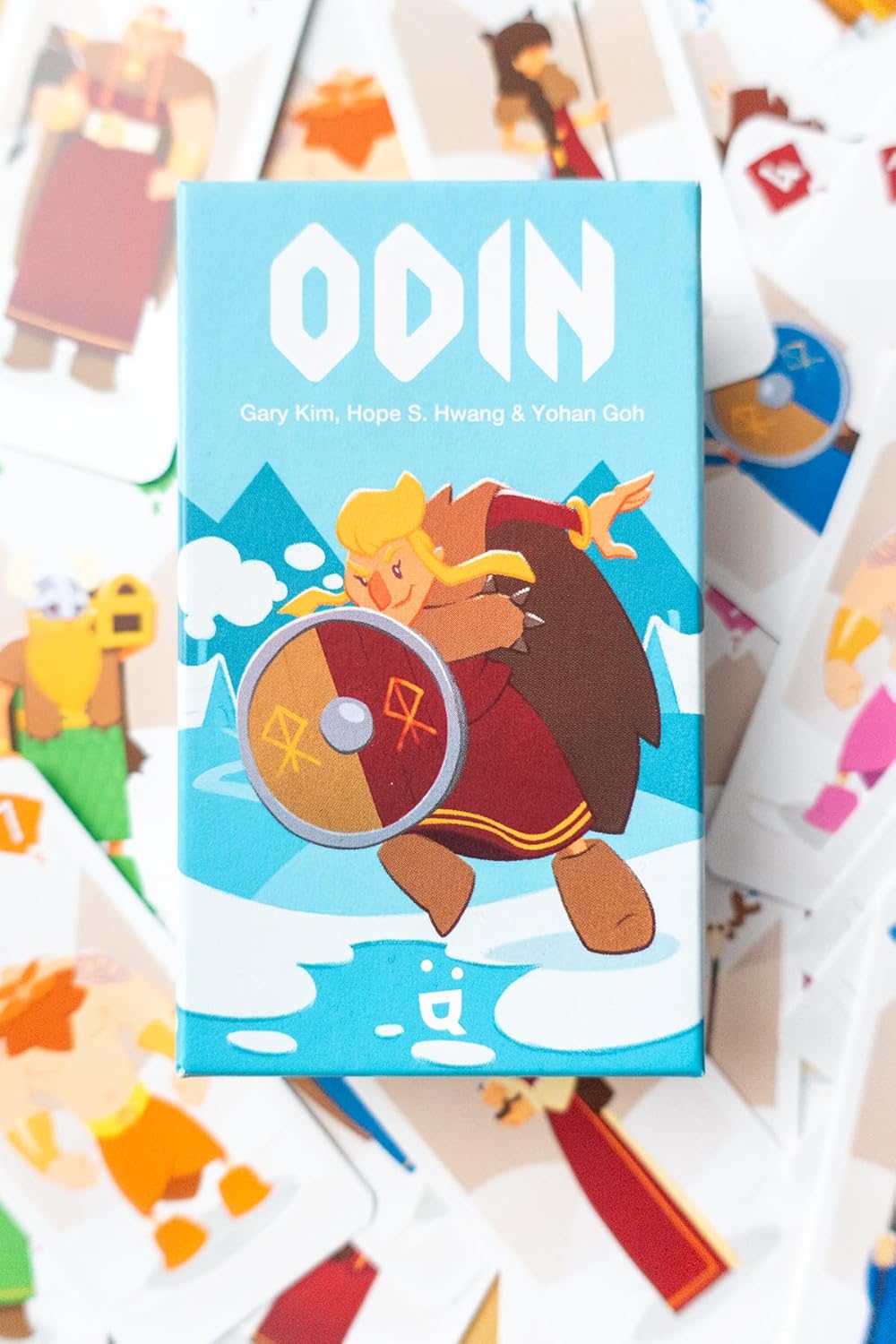 Card game box titled 'ODIN' with a character holding a shield on a blue background, surrounded by other cards.