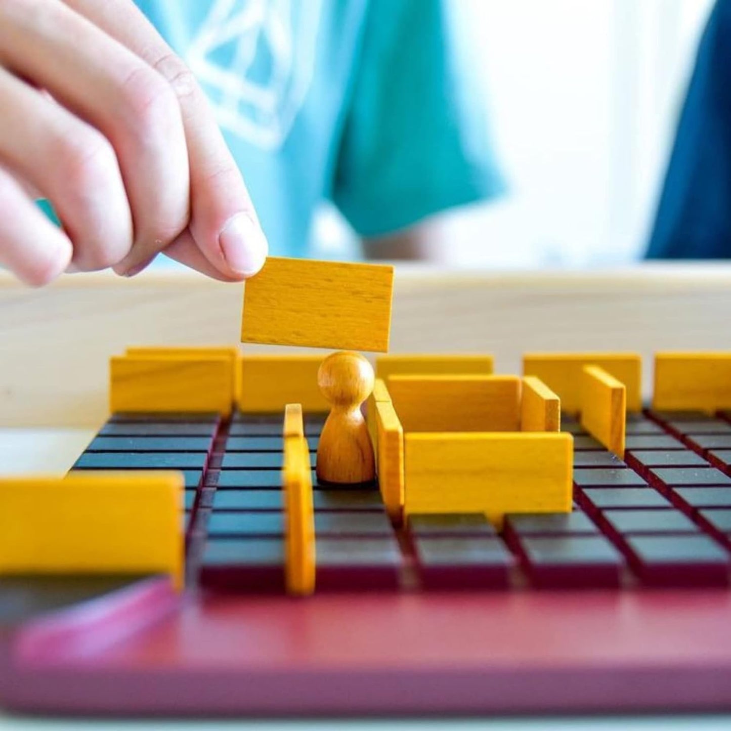 Hand placing wooden blocks on a game board with a blurred background