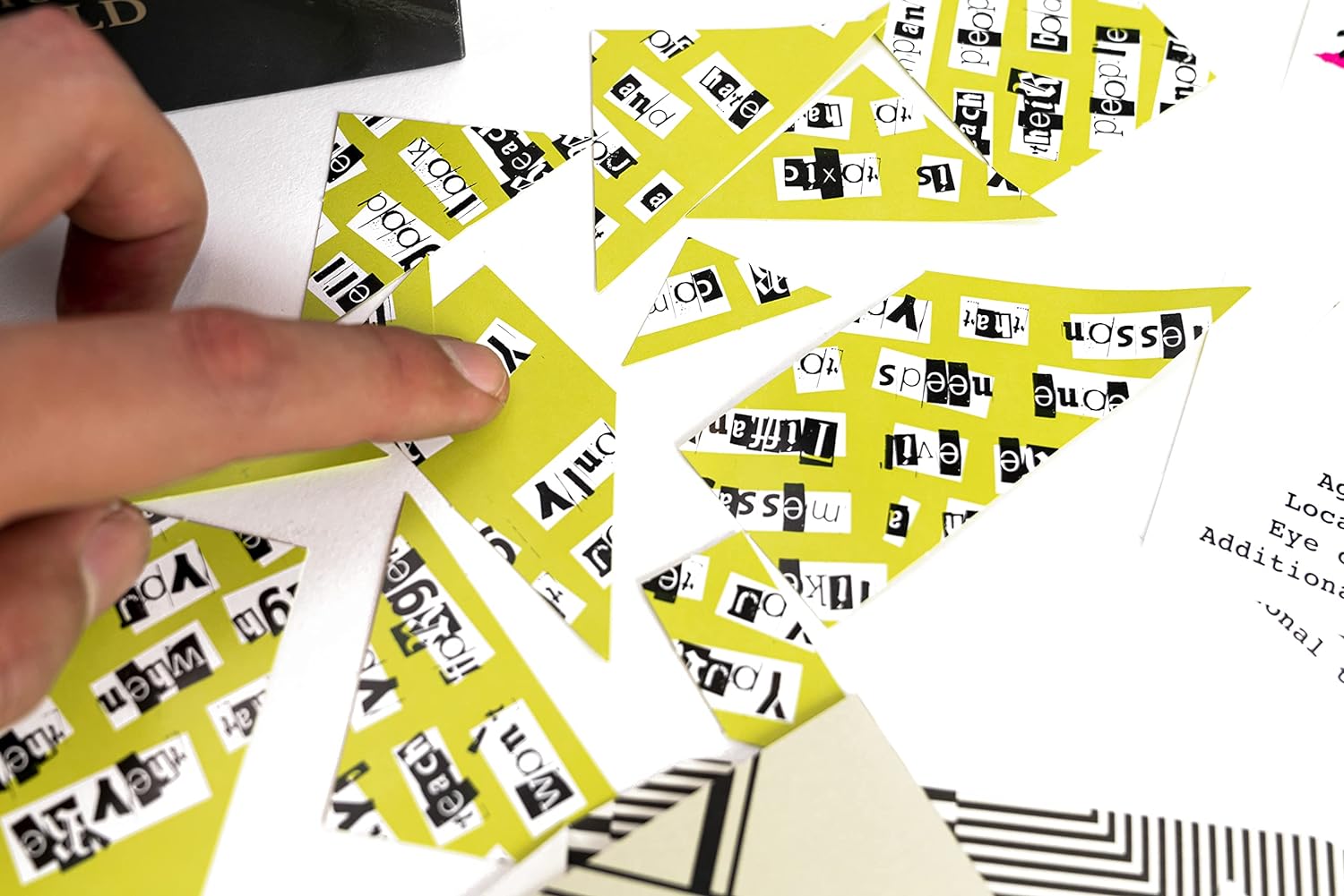 Hand interacting with yellow and black patterned cards on a white surface