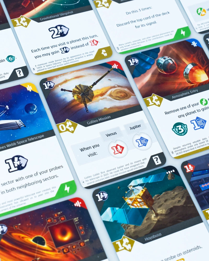 A close-up, angled view of several overlapping cards SETI: search for extraterrestrial intelligence board game, showing space-themed artwork, resource icons, and game text on a white background.