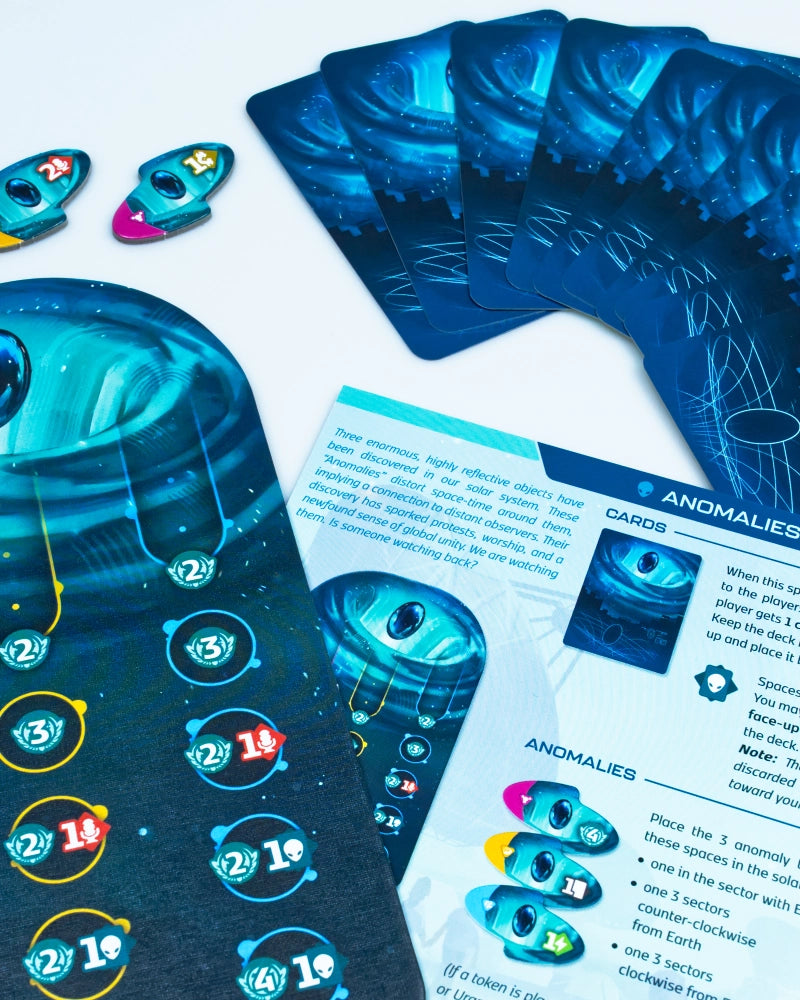 A close-up of a blue card game set for SETI: search for extraterrestrial intelligence board game on a white surface, showing illustrated cards, tokens, and a game board with printed rules or instructions.