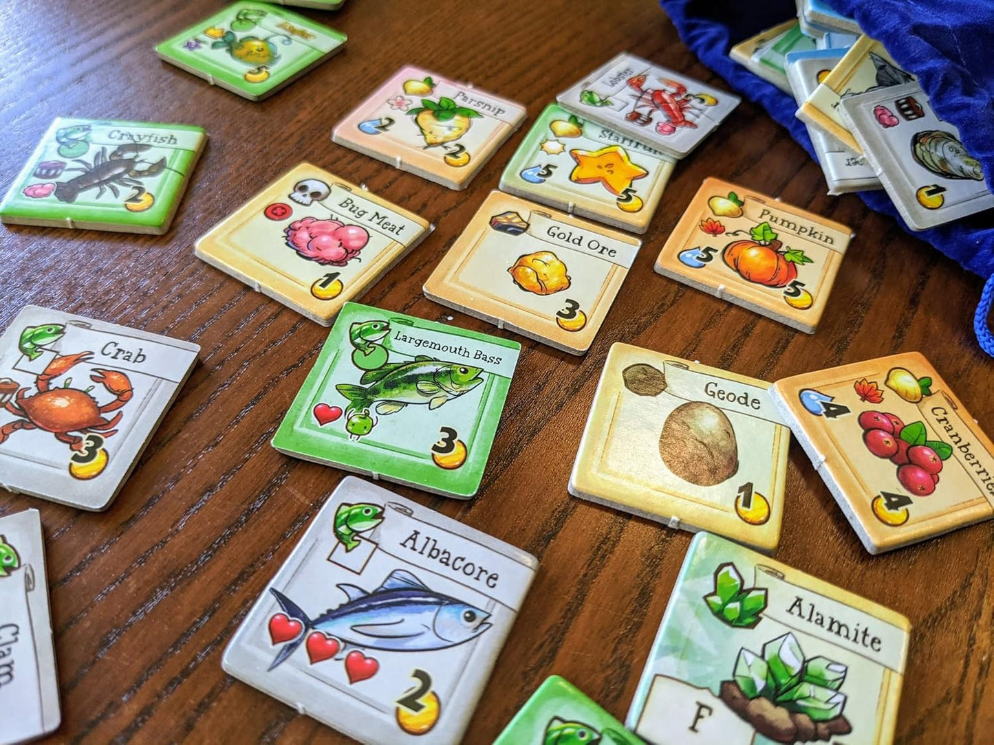 Collection of colourful game cards for Stardew Cooperative farming board game on a wooden surface