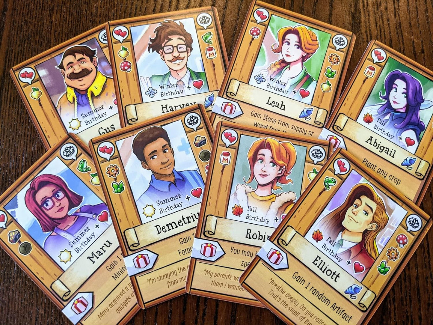 Collection of character cards with illustrated faces and names for Stardew Cooperative farming board game on a wooden surface
