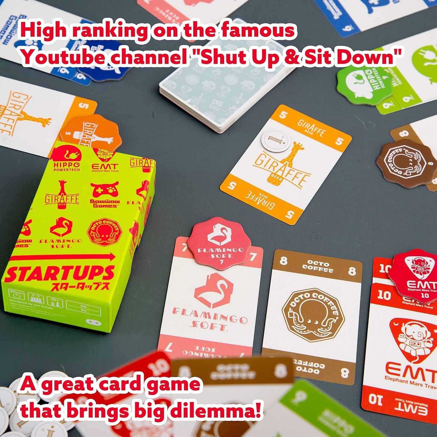 Startups card game with various cards and a box on a dark surface, featuring text about the game's ranking on a YouTube channel.
