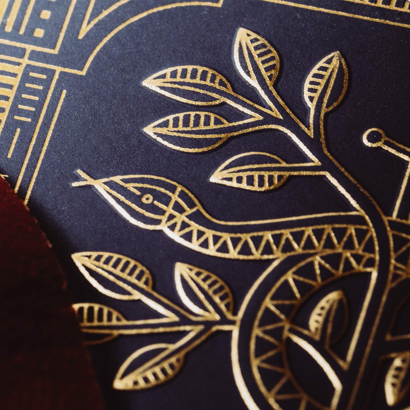 Close-up of a dark blue fabric with gold embroidered snake and leaf design