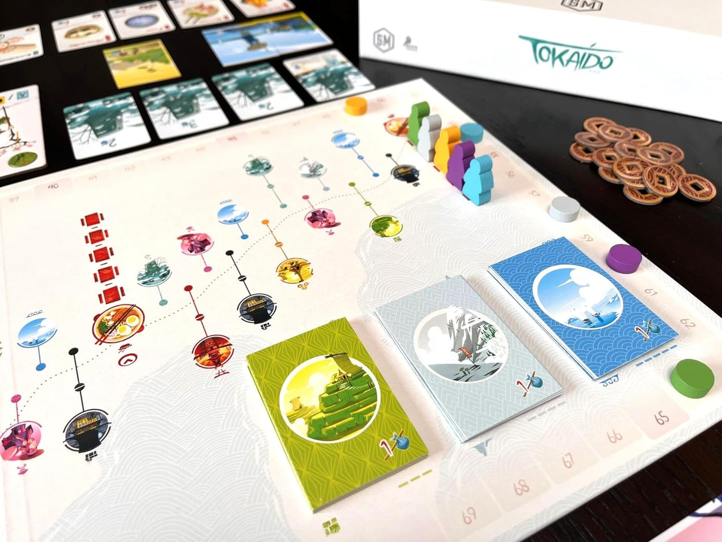 Board game setup with cards and pieces on a white surface, featuring the brand 'TOKAIDO'.