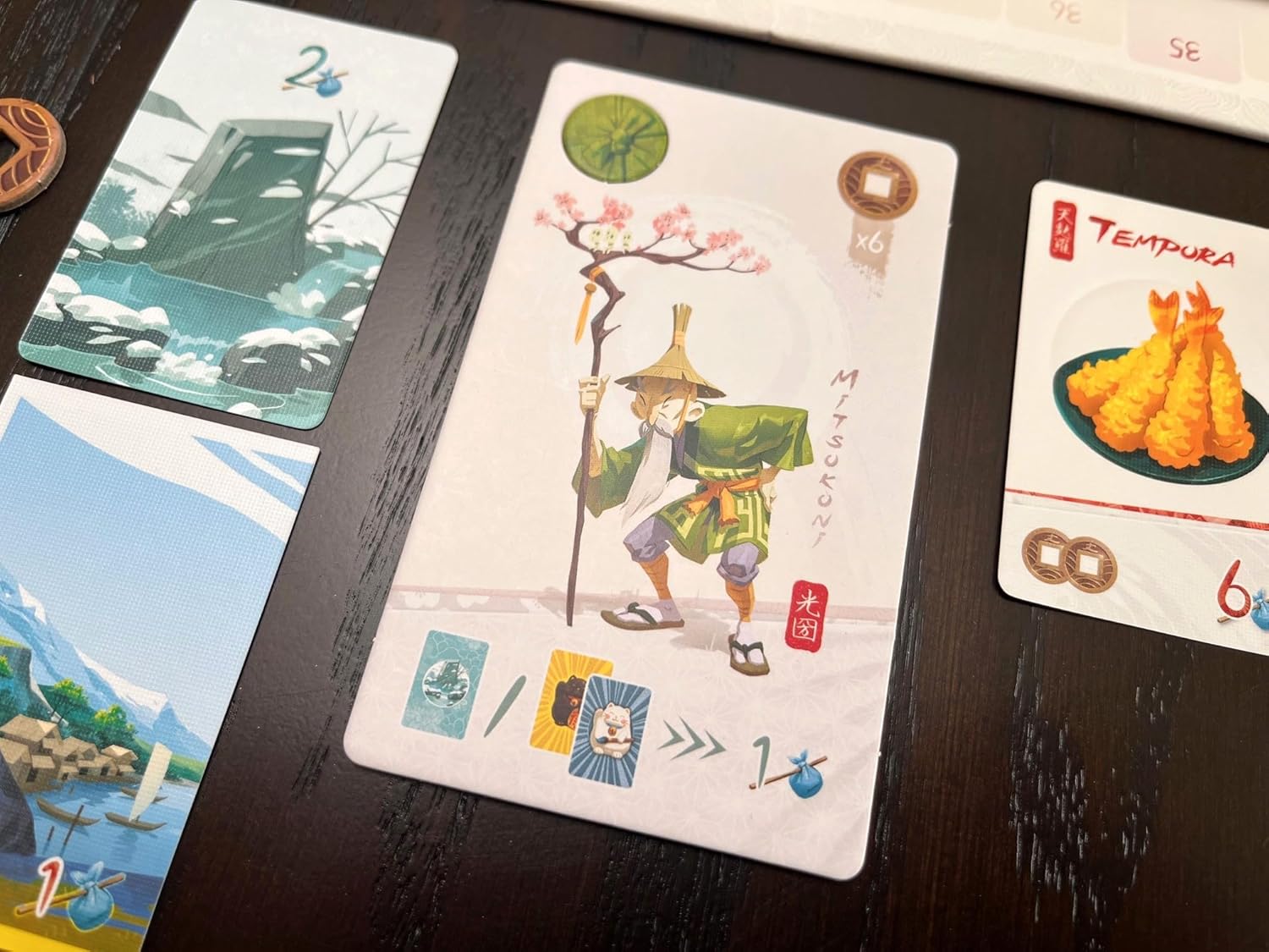 Card game with scenic and character-themed cards on a dark surface