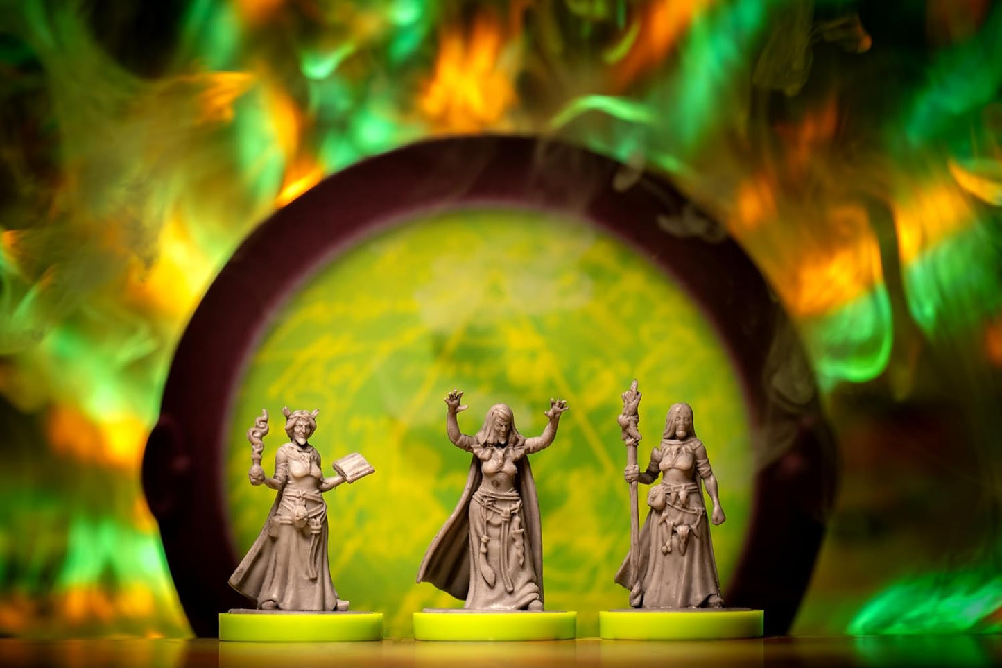Three miniature figurines of the Wayward Sisters with a colourful, blurred background
