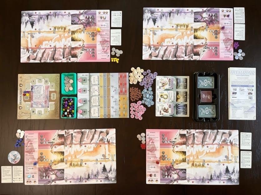 Collection of board game components including cards, pieces, and boards on a dark surface.
