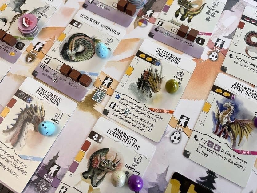 Collection of board game cards with various creatures and game pieces on a white surface