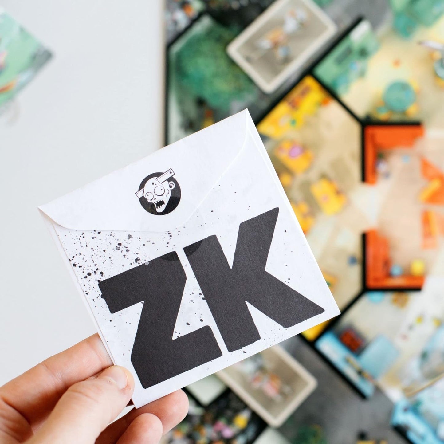 Hand holding a card with 'ZK' printed on it, with a blurred background of colourful board games.